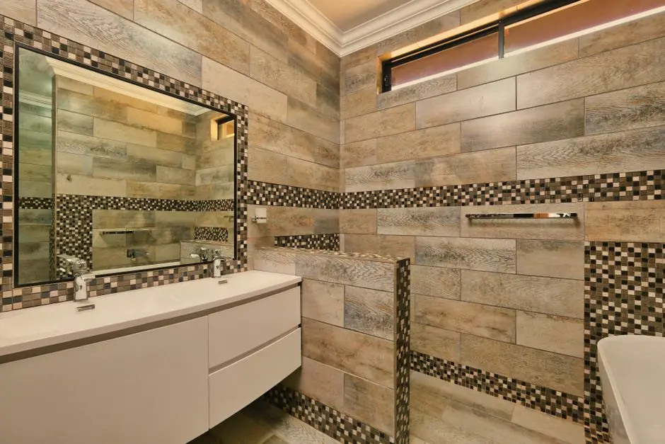 Elegant bathroom featuring mosaic tiles, large mirror, and minimalist sink design.